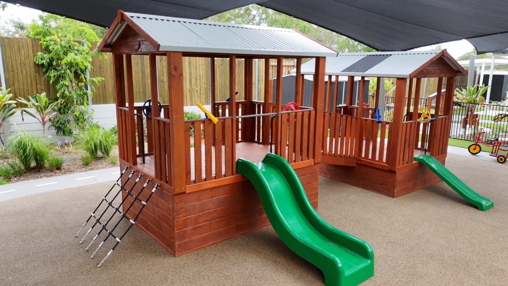 Wooden cubby houses with green slides and climbing nets at Greenbank Covella